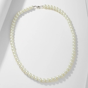 Detail of white 8mm glass pearls with silver lobster clasp on elegant white fabric