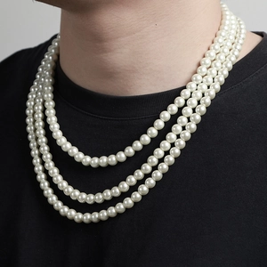 Close-up of three-layer white pearl necklace on a model wearing a black shirt