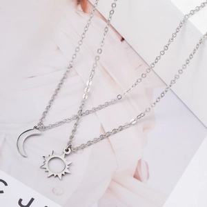 Detail of silver sun and moon friendship pendants on a minimalist stainless steel chain