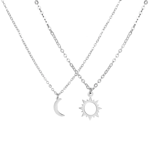 Close-up of polished stainless steel sun and moon pendants on minimalist chains