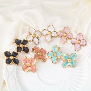 Floral stainless steel earrings in multiple colors on elegant white ceramic dish