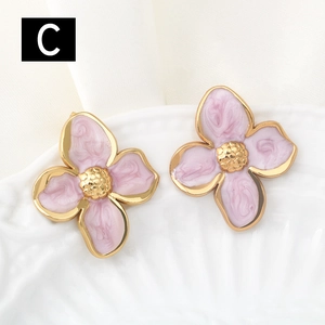 Macro view of pink marble flower earrings with gold finish on white ceramic plate