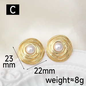 Macro view of gold vintage earrings with spiral texture and white pearl inlay detail