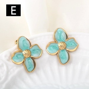 Macro detail of mint green floral enamel earrings with gold textured center and edges
