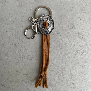 Vintage Western cowboy leather fringe keychain with engraved silver metal charm on grey background