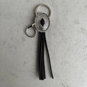 Detail of western vintage keychain with silver floral metal and long black leather tassels
