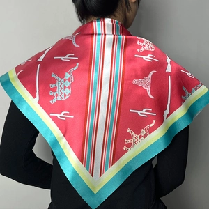 Detail of bohemian red silk scarf with elephant and cactus prints worn by a model