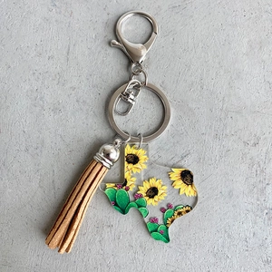 Macro view of Texas map acrylic keychain with sunflower, cactus prints and suede tassel