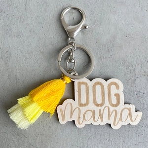Détail du porte-clés DOG mama en bois avec pompon jaune dégradé et fermoir mousqueton