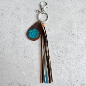 Crazy horse leather sunflower keychain with tassel and silver lobster clasp on cement surface