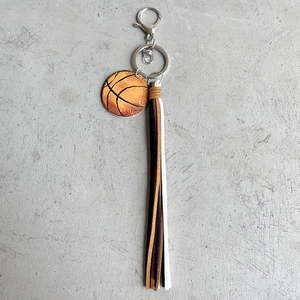 Vintage basketball keychain with realistic texture and tricolor leather tassels on grey stone