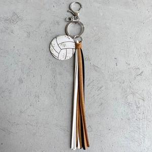 Detail of volleyball charm keychain with vintage leather tassels and metal lobster clasp