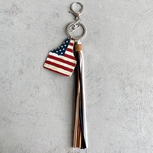 Detail of western cowboy keychain featuring US flag ear tag and long leather tassels