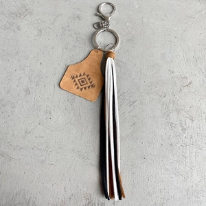 Porte-clés azteque en cuir avec franges et mousqueton sur un fond gris neutre