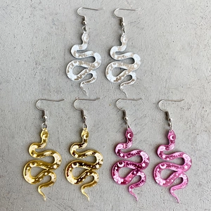 Close-up of three pairs of acrylic snake earrings with floral and celestial patterns