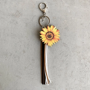 Detail of wooden sunflower charm keychain with stylish leather fringe tassels