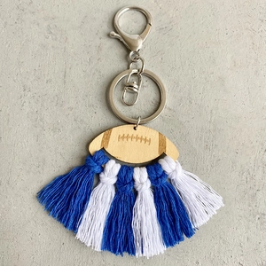 Detail of laser-engraved wood football charm with blue and white cotton tassels