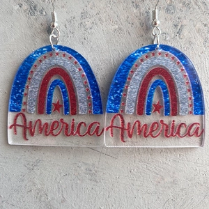 Detailed view of American flag inspired rainbow acrylic earrings with America text