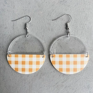 Minimalistische Acryl-Ohrringe mit orangefarbenem Karomuster auf grauem Hintergrund