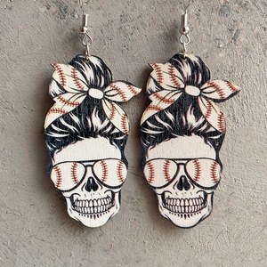 Close-up of wooden skull earrings with messy bun and baseball pattern on stone background