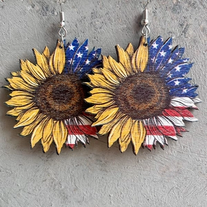 Close-up of wooden sunflower earrings with American flag patterns on a grey stone surface
