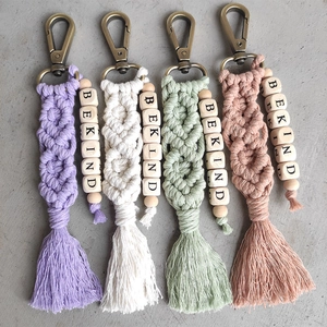Detail of four handmade macrame keychains with BE KIND wooden beads and tassels