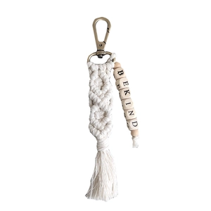 Handmade macrame keychain with BE KIND wooden beads and cotton tassels on white background