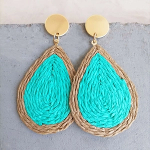 Handmade teardrop rattan earrings with blue and beige woven textures on a grey stone base