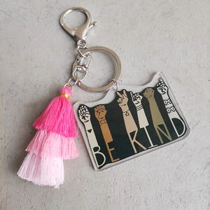 Detail of acrylic BE KIND keychain featuring pink tassel and silver lobster clasp