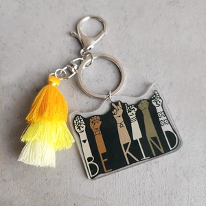Macro view of Be Kind acrylic pendant with yellow gradient tassel and silver clasp