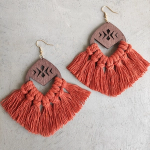 Detail of bohemian wood geometric drop earrings with dense rust red woven tassels