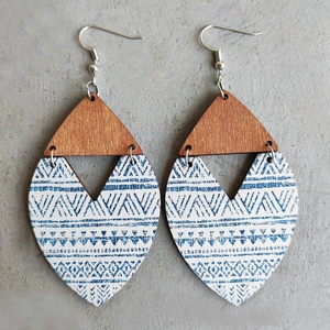 Detail of bohemian wooden drop earrings with blue ethnic patterns on cement background