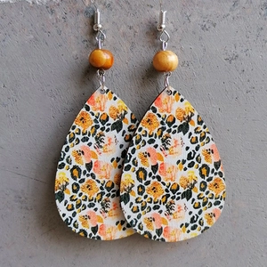 Detail of bohemian teardrop wooden earrings with yellow floral and leopard print patterns