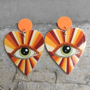 Detail of heart-shaped drop earrings with pop art eye motif and vibrant colorful rays