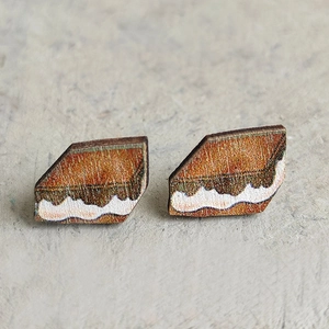Macro detail of trapezoid wooden stud earrings featuring abstract mountain landscape patterns