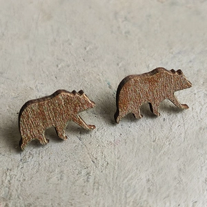 Detail showing laser-cut brown wooden bear earrings with realistic grain texture