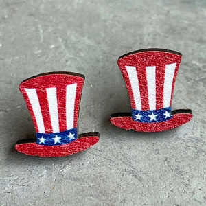 Macro shot of Uncle Sam hat earrings with American flag patterns on stone surface
