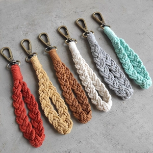 Handmade macrame keychains in six colors with bronze lobster clasps on gray surface