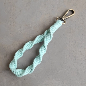 Close-up of sage green spiral woven cotton keychain with bronze metal lobster clasp detail
