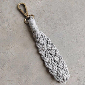 Close-up of handmade bohemian woven cotton rope keychain with antique bronze metal clasp