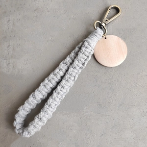 Détail d'un porte-clés bohème en macramé gris fait main avec médaillon en bois et fermoir