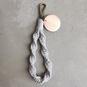 Detail of grey handmade macrame keychain with wooden tag and bronze lobster clasp