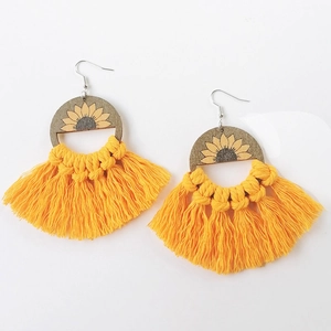 Detail of bohemian sunflower wooden earrings with bright yellow woven cotton tassels