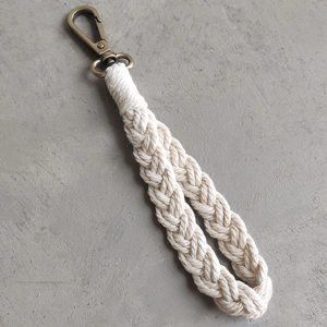Close-up of hand-woven bohemian cotton rope keychain with vintage bronze metal hook