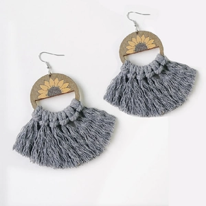 Detailed macro view of bohemian earrings with sunflower wood charms and gray fringe tassels