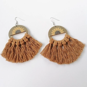Detailed view of bohemian wood sunflower earrings with brown woven cotton tassels