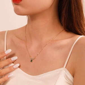 Dettaglio della collana dorata con pendente a goccia verde e micro zirconi incastonati