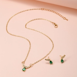 Dettaglio di set di gioielli con collana dorata e orecchini in zircone verde