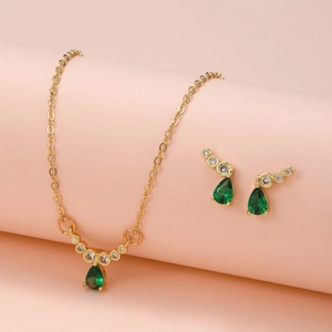 Dettaglio del ciondolo a goccia con zircone verde e orecchini su sfondo rosa
