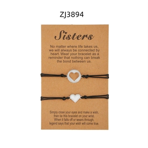 Dettaglio di braccialetti a cuore per sorelle con corda nera intrecciata e scheda